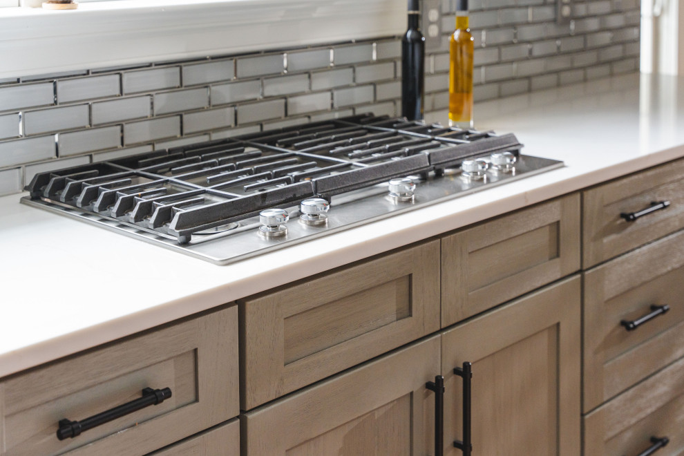 Large transitional u-shaped medium tone wood floor and brown floor eat-in kitchen photo with a farmhouse sink, shaker cabinets, gray cabinets, quartz countertops, gray backsplash, glass tile backsplash, stainless steel appliances, an island and white countertops