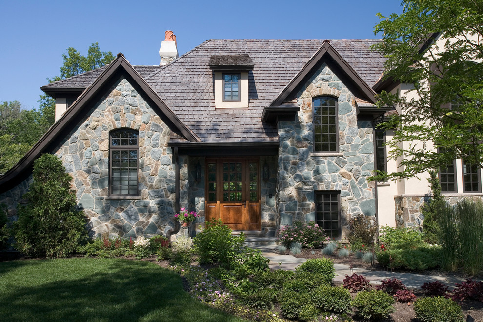 Photo of a large traditional two-storey beige exterior in Chicago with stone veneer and a hip roof.