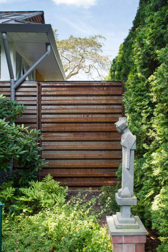 Foto di un giardino xeriscape minimalista esposto a mezz'ombra di medie dimensioni e dietro casa in estate con cancello, pacciame e recinzione in metallo