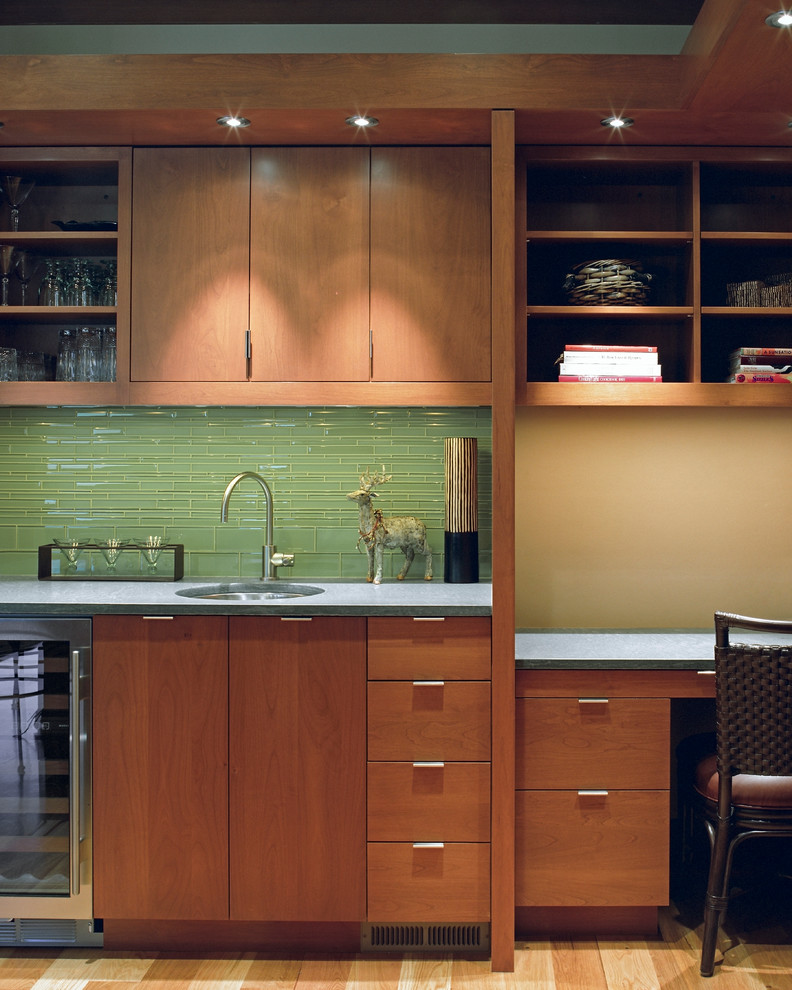 This is an example of a mid-sized contemporary single-wall wet bar in Seattle with an undermount sink, flat-panel cabinets, medium wood cabinets, solid surface benchtops, green splashback, matchstick tile splashback, light hardwood floors and beige floor.