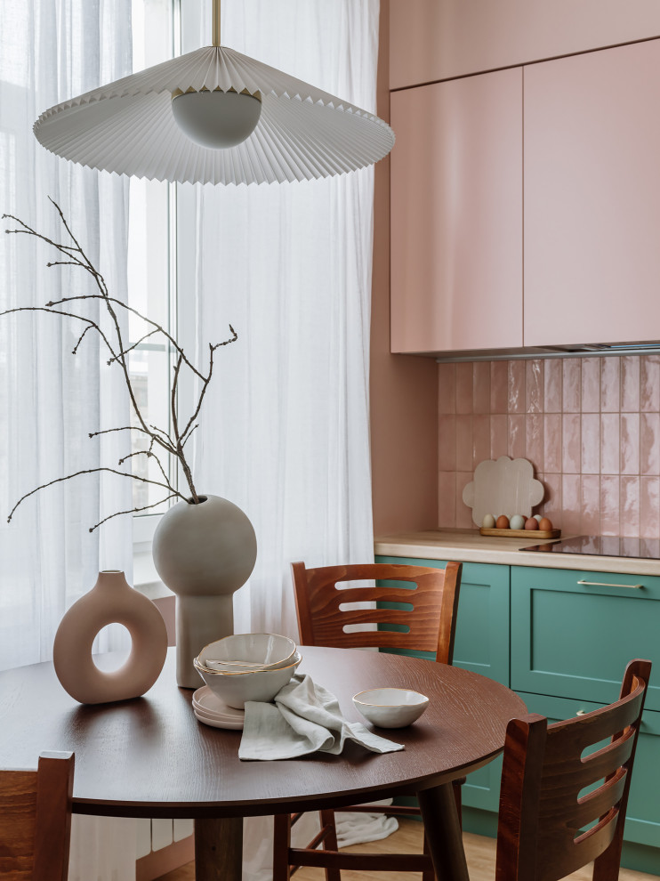 Идея дизайна: угловая кухня-гостиная среднего размера в стиле ретро с накладной мойкой, зелеными фасадами, розовым фартуком, фартуком из керамической плитки и черной техникой без острова