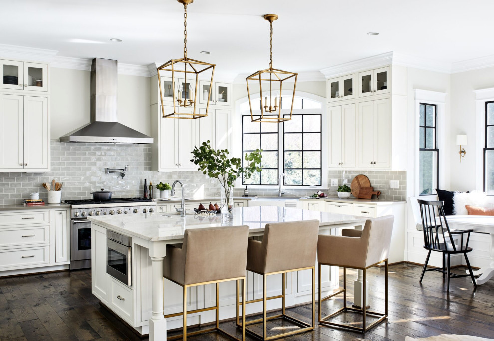 Design ideas for a transitional u-shaped eat-in kitchen in DC Metro with a farmhouse sink, shaker cabinets, white cabinets, grey splashback, subway tile splashback, stainless steel appliances, medium hardwood floors, with island, brown floor and grey benchtop.