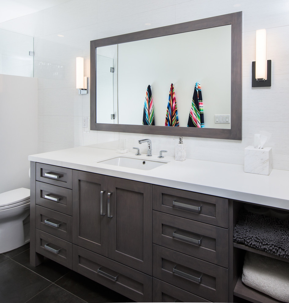 Photo of a mid-sized transitional master bathroom in Los Angeles with recessed-panel cabinets, grey cabinets, an alcove shower, a one-piece toilet, white tile, white walls, an undermount sink, black floor and a hinged shower door.