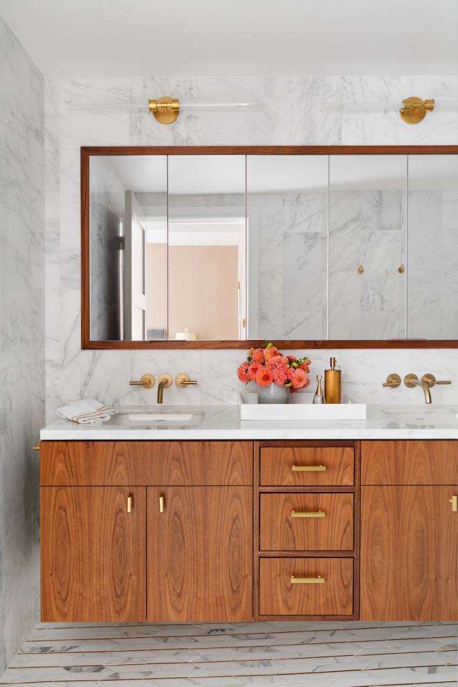 This is an example of a large contemporary ensuite bathroom in New York with flat-panel cabinets, medium wood cabinets, a one-piece toilet, white tiles, marble tiles, white walls, marble flooring, a submerged sink, engineered stone worktops, white floors, white worktops, double sinks and a floating vanity unit.