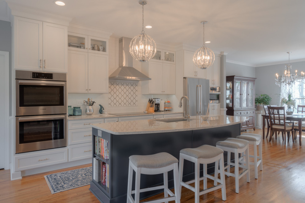 Mid-sized transitional galley medium tone wood floor eat-in kitchen photo with an undermount sink, flat-panel cabinets, white cabinets, quartz countertops, white backsplash, subway tile backsplash, stainless steel appliances, an island and white countertops