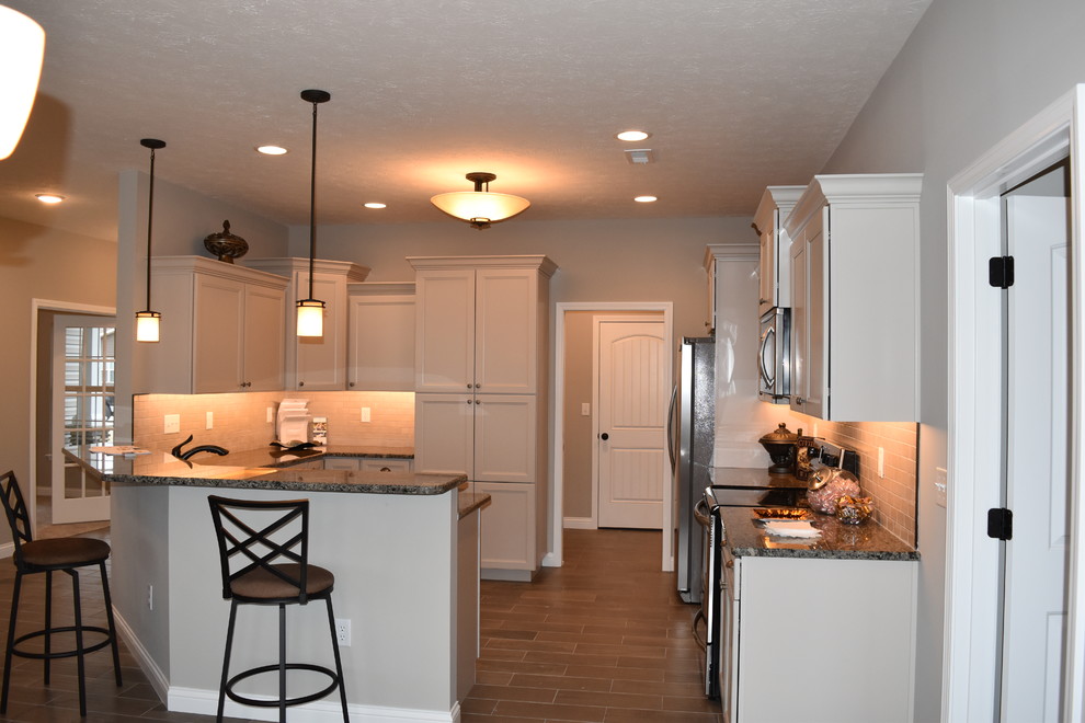 Mid-sized transitional u-shaped porcelain tile enclosed kitchen photo with an undermount sink, recessed-panel cabinets, beige cabinets, granite countertops, beige backsplash, subway tile backsplash, stainless steel appliances and a peninsula