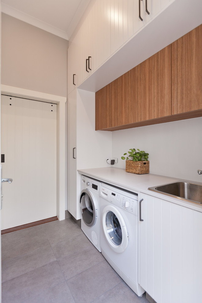 Small contemporary galley utility room in Perth with a drop-in sink, light wood cabinets, quartz benchtops, grey walls, porcelain floors, a side-by-side washer and dryer, grey floor and white benchtop.