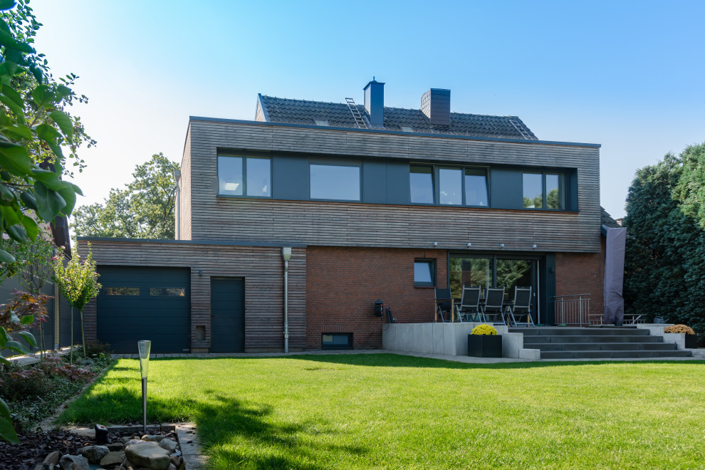 This is an example of a mid-sized modern one-storey grey house exterior in Essen with wood siding, a flat roof and clapboard siding.