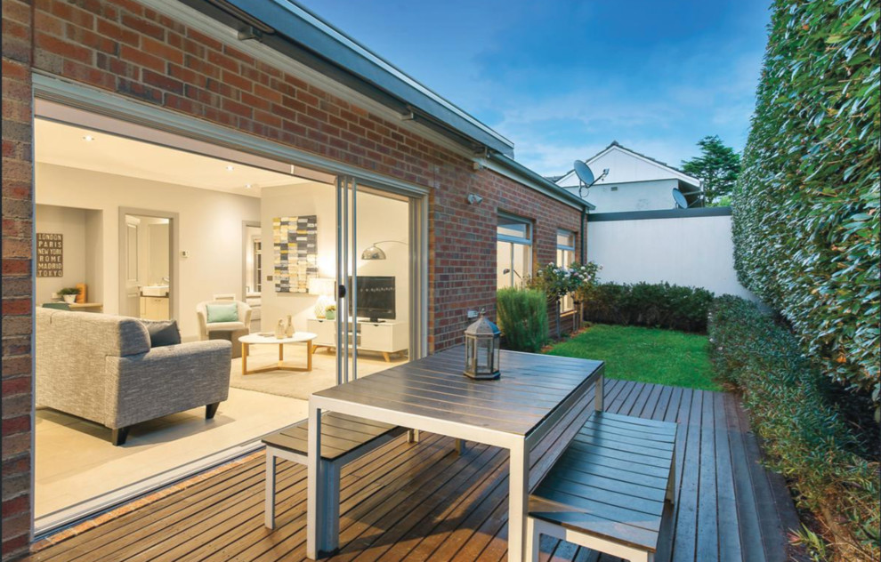 This is an example of a small contemporary backyard patio in Melbourne with decking, a vertical garden and an awning.
