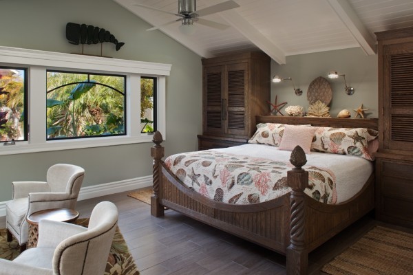 This is an example of a large beach style master bedroom in San Diego with green walls, laminate floors, no fireplace and brown floor.