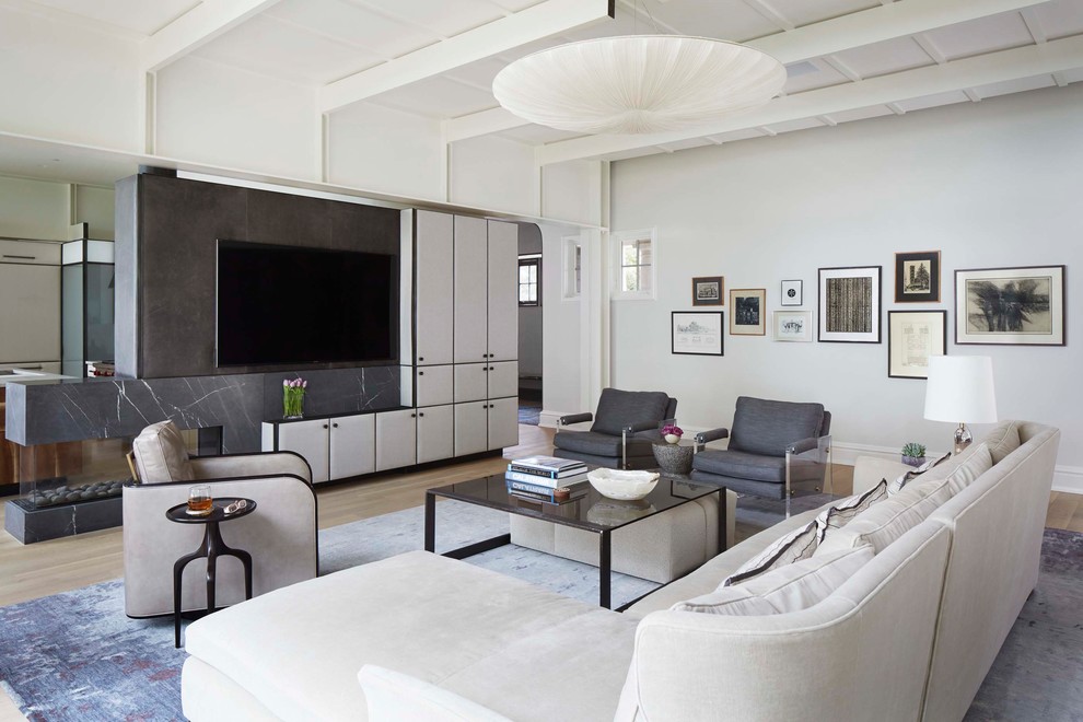 This is an example of a contemporary family room in Chicago with white walls, light hardwood floors, a two-sided fireplace, a stone fireplace surround, a wall-mounted tv and beige floor.