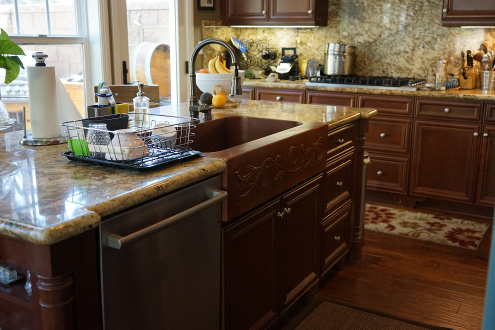 Design ideas for a large country eat-in kitchen in Los Angeles with a farmhouse sink, beaded inset cabinets, dark wood cabinets, granite benchtops, granite splashback, stainless steel appliances, dark hardwood floors, with island and brown floor.