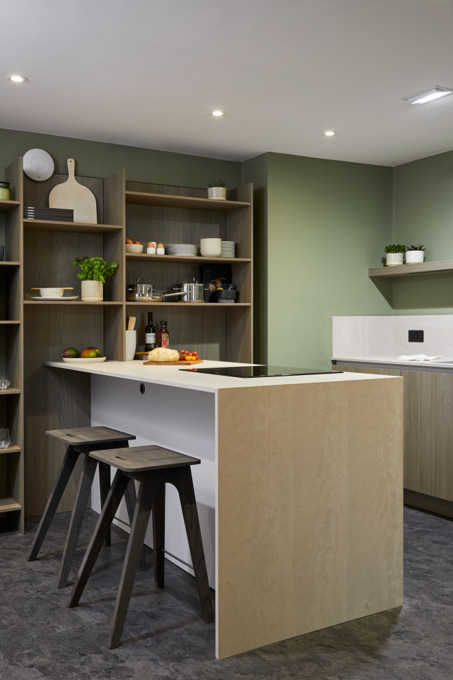 Small modern kitchen in London with an undermount sink, flat-panel cabinets, medium wood cabinets, quartz benchtops, beige splashback, engineered quartz splashback, black appliances, with island and beige benchtop.
