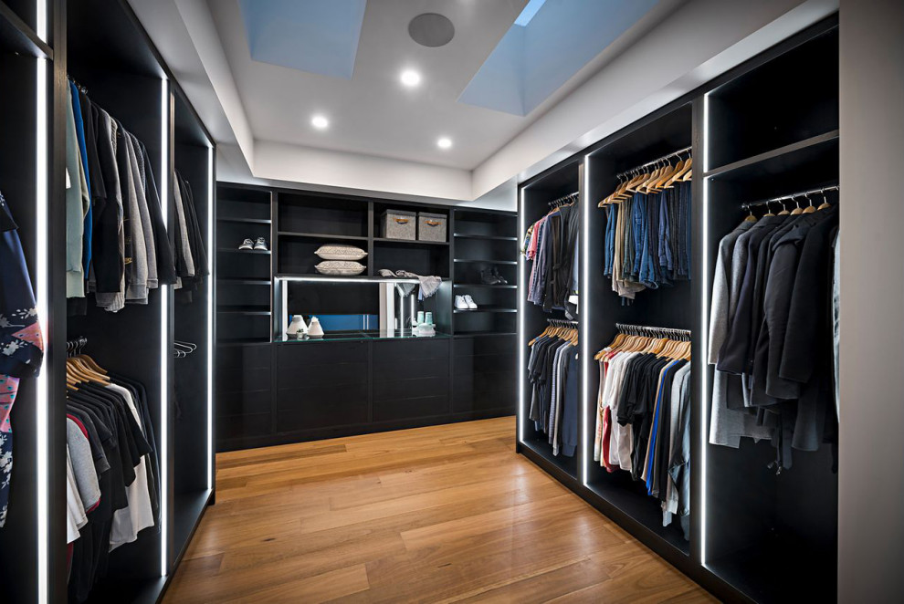 Photo of a large contemporary gender-neutral walk-in wardrobe in Melbourne with open cabinets, black cabinets, medium hardwood floors and recessed.