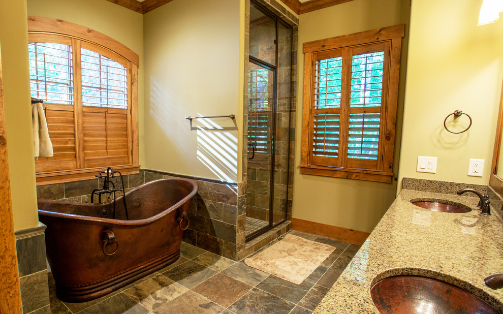 Photo of a large arts and crafts master bathroom in Other with an undermount sink, raised-panel cabinets, dark wood cabinets, granite benchtops, a freestanding tub, an alcove shower, a one-piece toilet, multi-coloured tile, stone tile, yellow walls and slate floors.