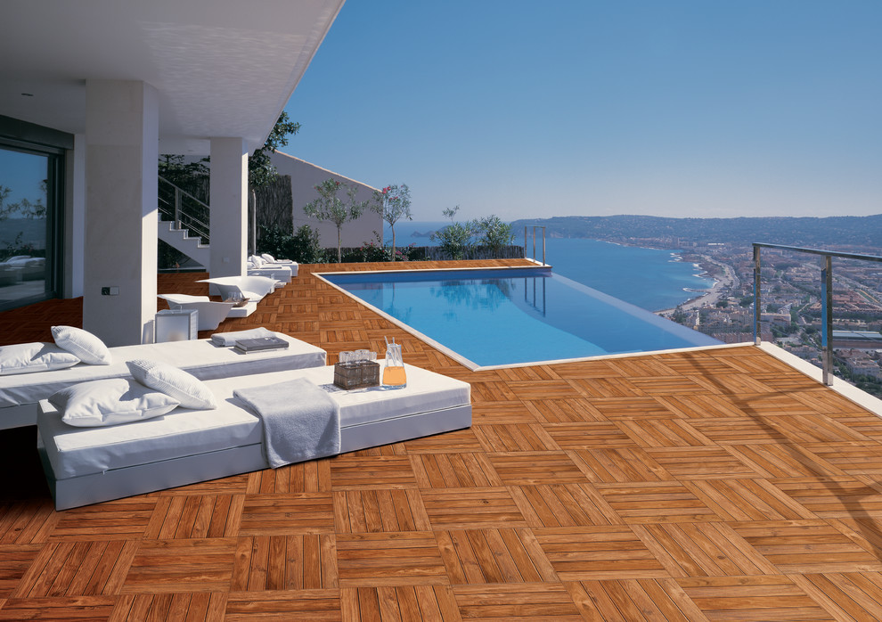 Contemporary rooftop rectangular infinity pool in Other with tile.