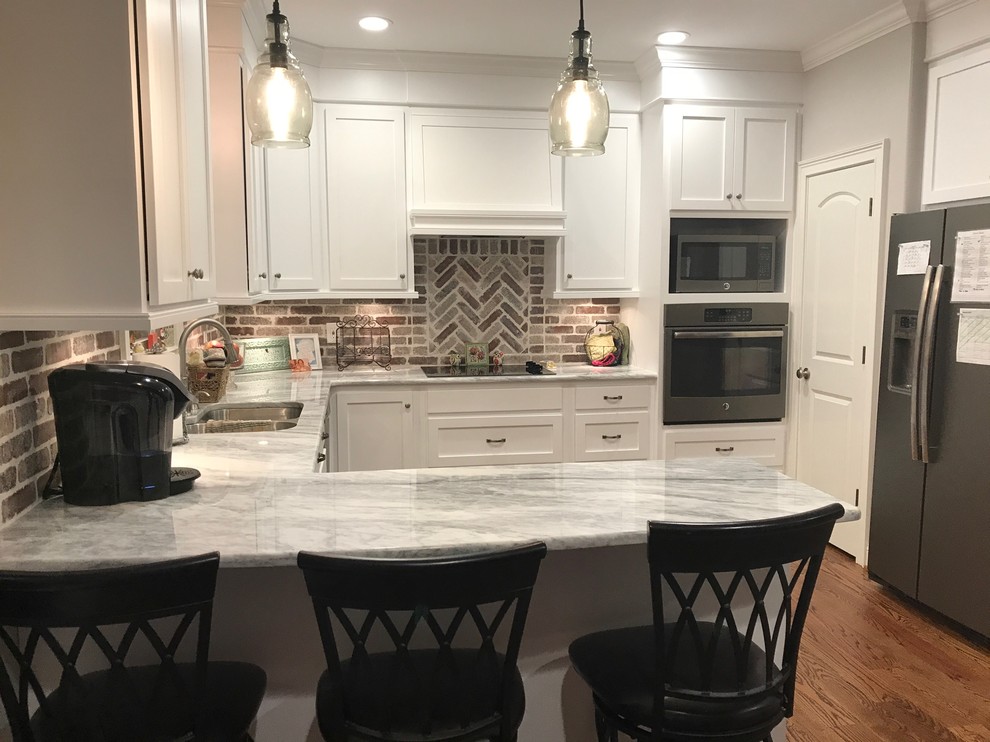 Large transitional u-shaped medium tone wood floor and brown floor eat-in kitchen photo in Birmingham with a double-bowl sink, shaker cabinets, white cabinets, multicolored backsplash, stainless steel appliances and a peninsula