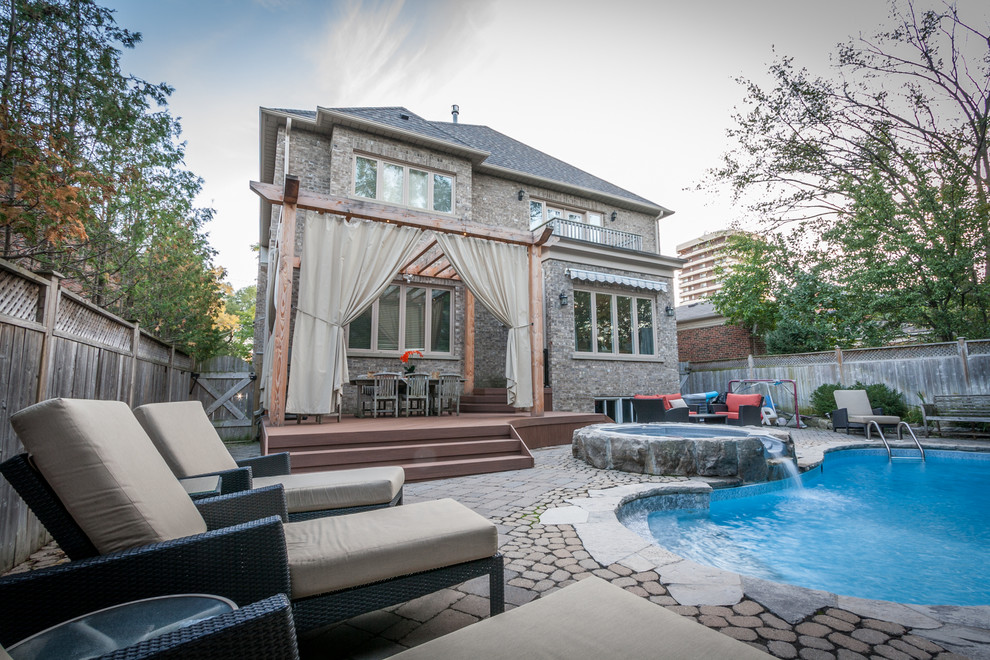 Mid-sized transitional backyard deck photo in Toronto with a pergola