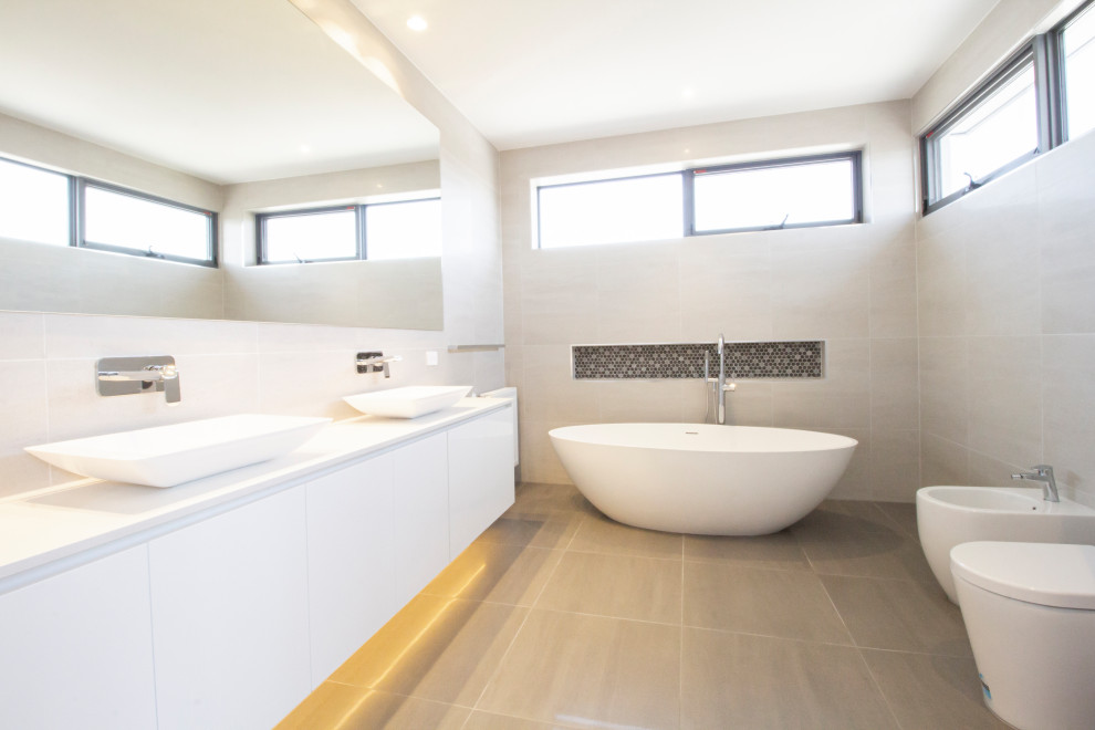 Large contemporary master bathroom in Melbourne with louvered cabinets, white cabinets, a freestanding tub, an open shower, a bidet, beige tile, cement tile, cement tiles, a vessel sink, concrete benchtops, grey floor, an open shower and white benchtops.