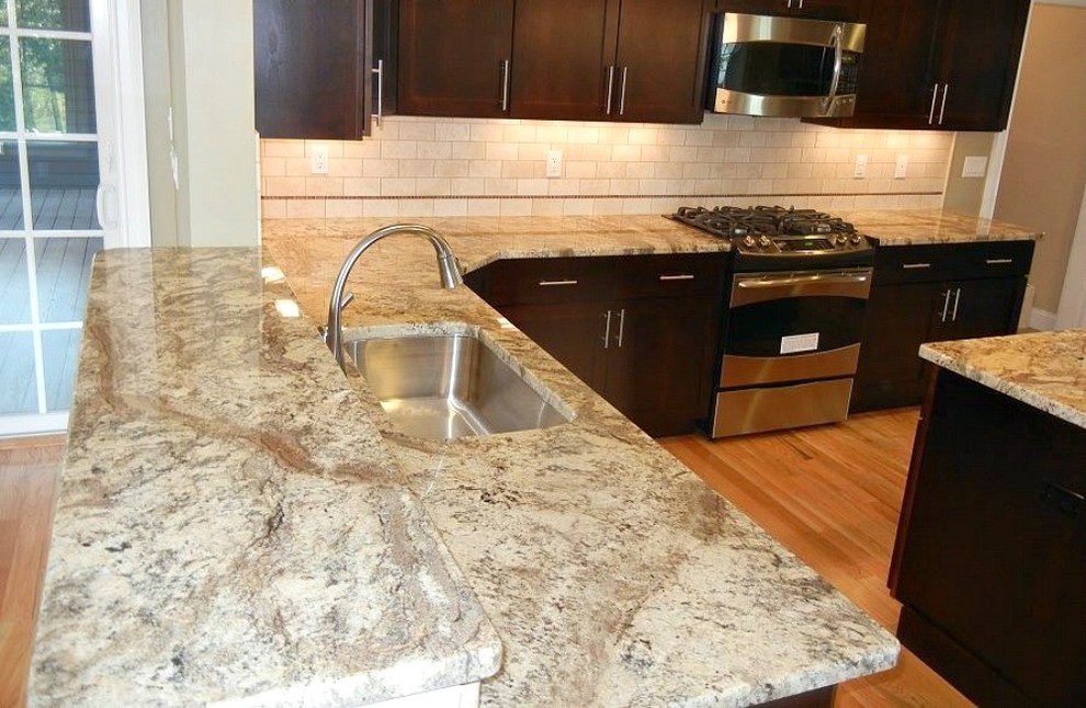 Example of a mid-sized transitional l-shaped medium tone wood floor eat-in kitchen design in Bridgeport with an undermount sink, shaker cabinets, dark wood cabinets, granite countertops, beige backsplash, subway tile backsplash, stainless steel appliances and an island
