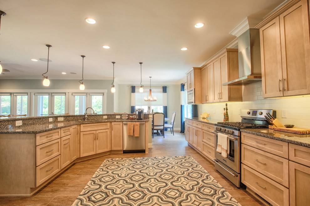 Large transitional single-wall porcelain tile and brown floor open concept kitchen photo with an undermount sink, recessed-panel cabinets, light wood cabinets, granite countertops, white backsplash, subway tile backsplash, stainless steel appliances, an island and gray countertops