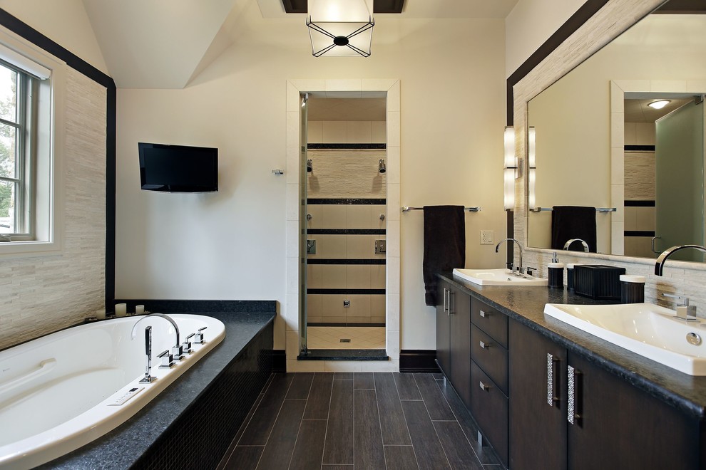 Contemporary bathroom in New York with flat-panel cabinets, a drop-in tub, white walls, a drop-in sink and dark wood cabinets.