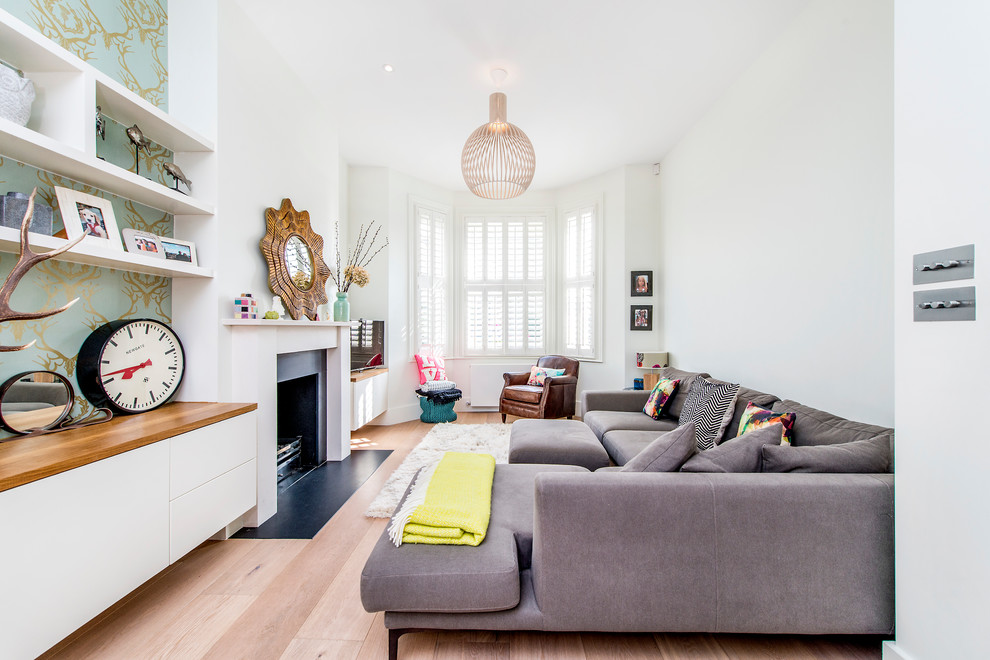 Inspiration for a contemporary formal living room in London with white walls, light hardwood flooring and a standard fireplace.