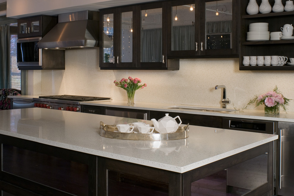 Photo of a modern eat-in kitchen in New York with an undermount sink, glass-front cabinets, dark wood cabinets, recycled glass benchtops, white splashback, cement tile splashback and stainless steel appliances.