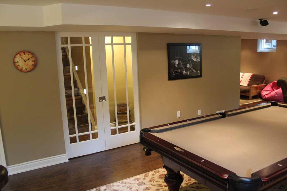 This is an example of a large traditional basement in Toronto with beige walls and dark hardwood floors.