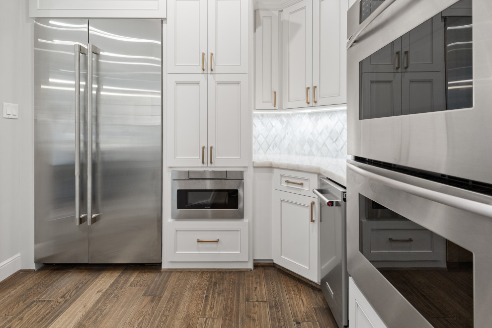 Eat-in kitchen - large transitional single-wall light wood floor and brown floor eat-in kitchen idea in Houston with a farmhouse sink, recessed-panel cabinets, white cabinets, quartzite countertops, white backsplash, mosaic tile backsplash, stainless steel appliances, an island and white countertops