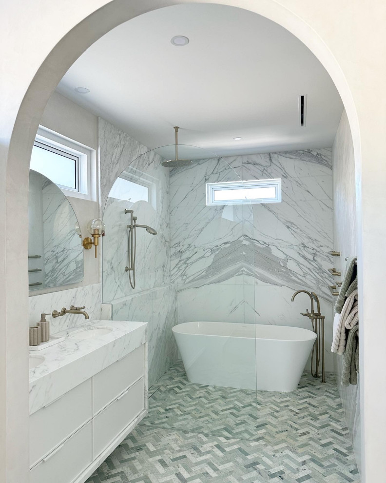 This is an example of a beach style bathroom in Geelong with shaker cabinets, white cabinets, a freestanding tub, an open shower, a wall-mount toilet, green tile, marble, beige walls, marble floors, an undermount sink, marble benchtops, green floor, an open shower, an enclosed toilet, a double vanity and a floating vanity.