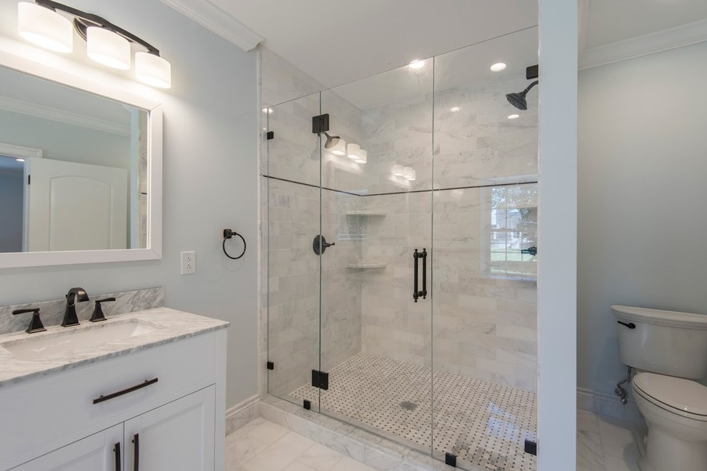 Design ideas for a mid-sized transitional master bathroom in Philadelphia with shaker cabinets, white cabinets, a freestanding tub, an alcove shower, a two-piece toilet, gray tile, stone tile, grey walls, marble floors, an undermount sink and marble benchtops.