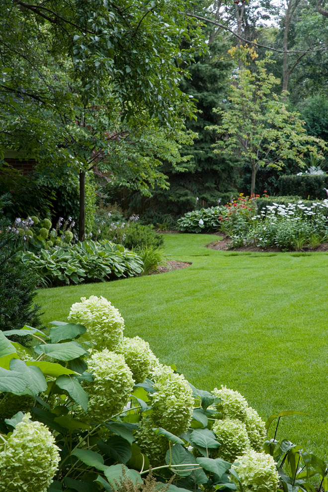 This is an example of a large traditional partial sun side yard stone formal garden in Chicago for summer.