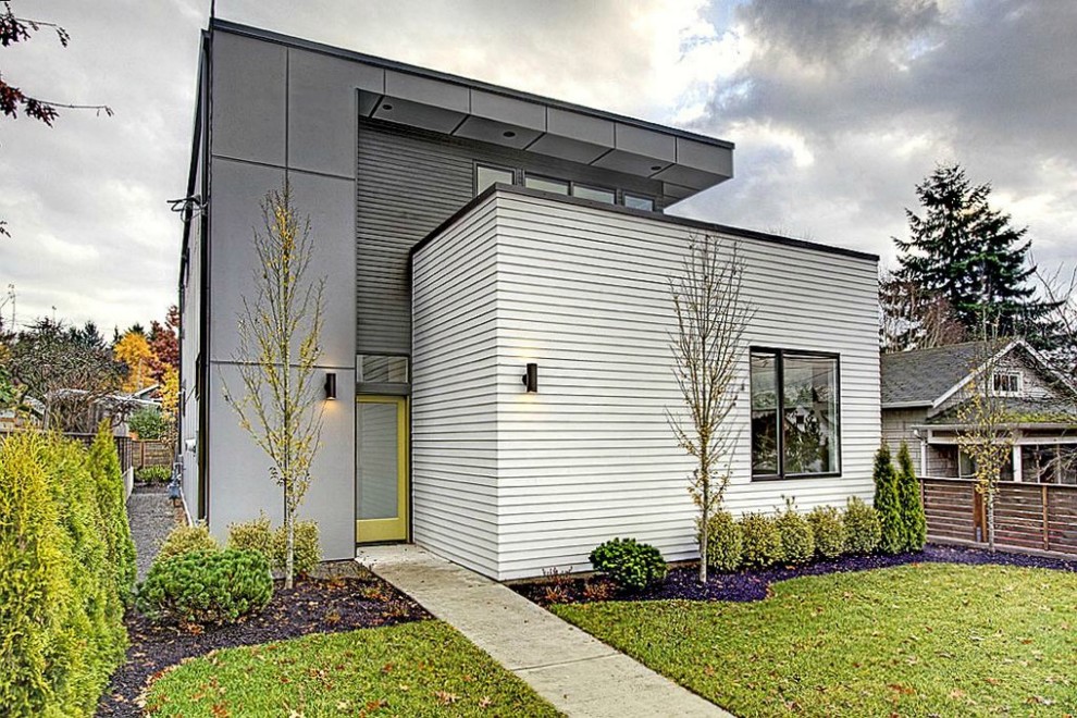 This is an example of a mid-sized contemporary two-storey grey exterior in Seattle with mixed siding and a flat roof.