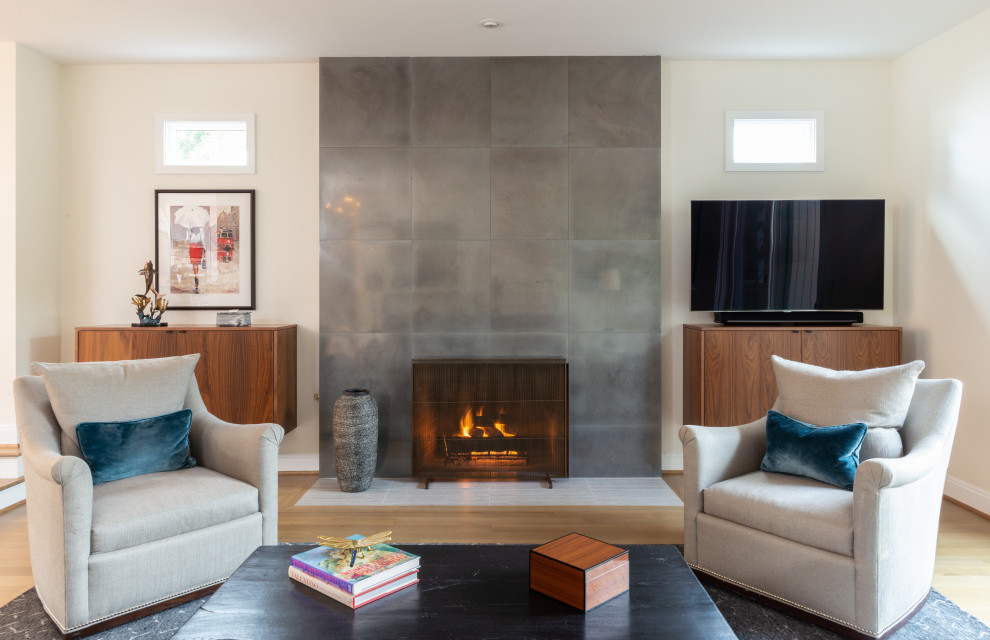 Inspiration for a contemporary open concept living room in Portland with white walls, light hardwood floors, a standard fireplace, a concrete fireplace surround, a freestanding tv and brown floor.