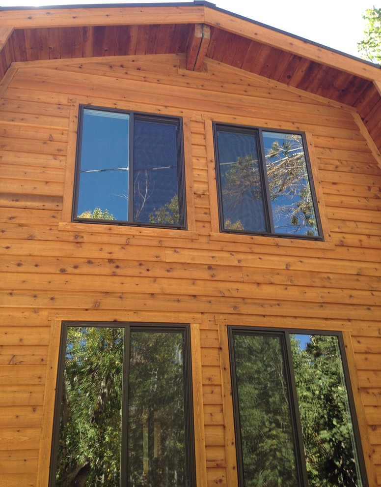 Example of a large mountain style brown two-story wood house exterior design with a metal roof