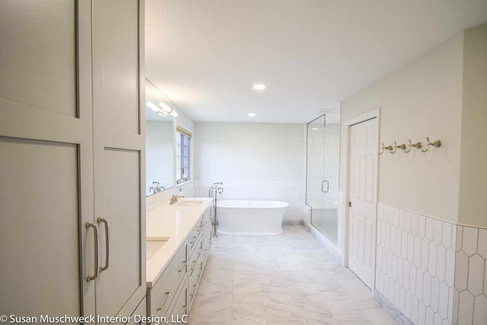 Large transitional master white tile and ceramic tile porcelain tile, white floor and double-sink freestanding bathtub photo with shaker cabinets, gray cabinets, a two-piece toilet, white walls, an undermount sink, quartz countertops, a hinged shower door, white countertops and a built-in vanity