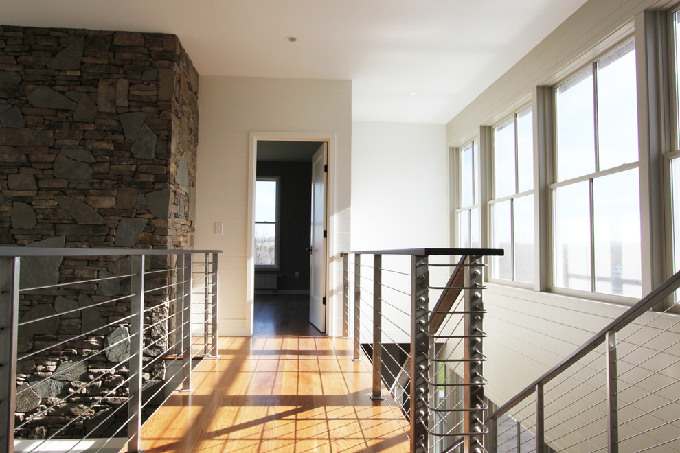 This is an example of a modern hallway in New York with white walls and medium hardwood floors.