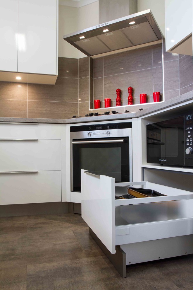 This is an example of a small contemporary u-shaped separate kitchen in Melbourne with flat-panel cabinets, white cabinets, laminate benchtops, porcelain splashback, vinyl floors and no island.