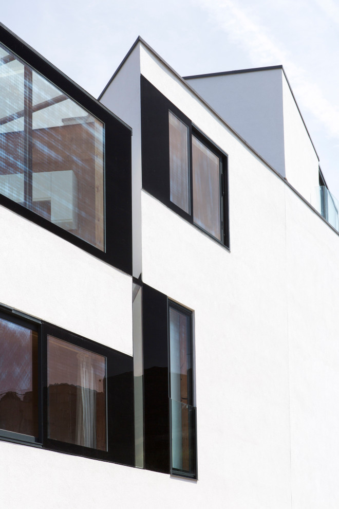 This is an example of a large contemporary stucco white exterior in London with four or more storeys and a flat roof.