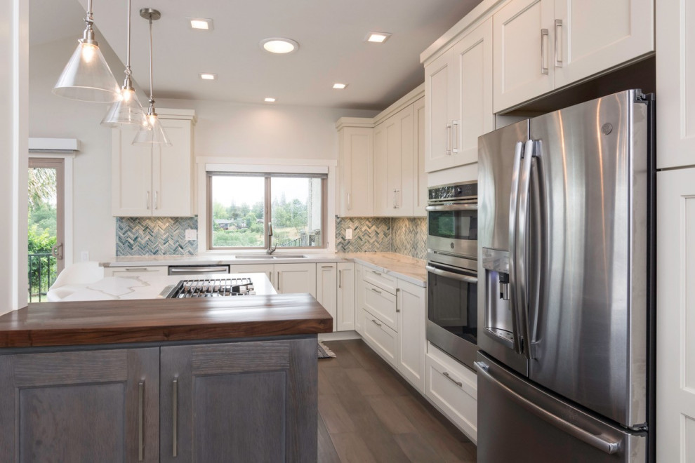 Large transitional l-shaped dark wood floor eat-in kitchen photo with an undermount sink, shaker cabinets, white cabinets, quartz countertops, blue backsplash, glass tile backsplash, stainless steel appliances, an island and white countertops