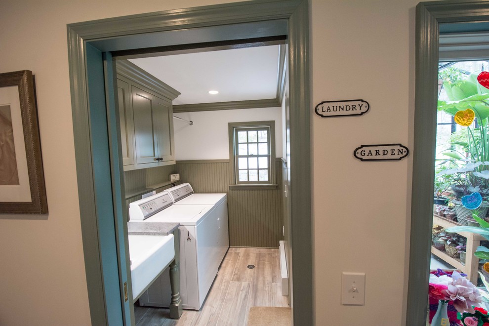Photo of a mid-sized traditional galley dedicated laundry room in New York with a farmhouse sink, beaded inset cabinets, green cabinets, soapstone benchtops, white walls, ceramic floors, a side-by-side washer and dryer and multi-coloured floor.