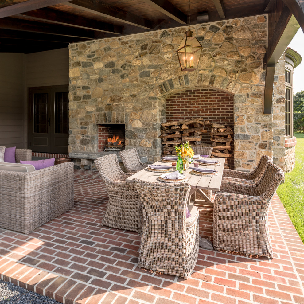 Photo of a small traditional side yard patio in Wilmington with brick pavers, a roof extension and with fireplace.