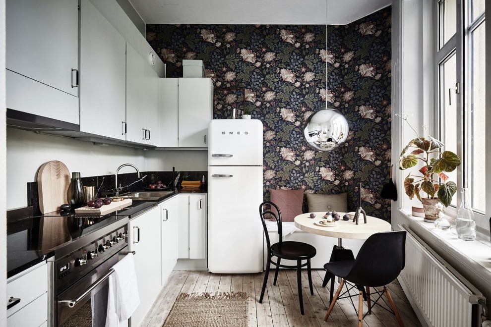 Photo of a mid-sized scandinavian l-shaped eat-in kitchen in Gothenburg with flat-panel cabinets, white cabinets, white appliances, light hardwood floors, no island and a double-bowl sink.