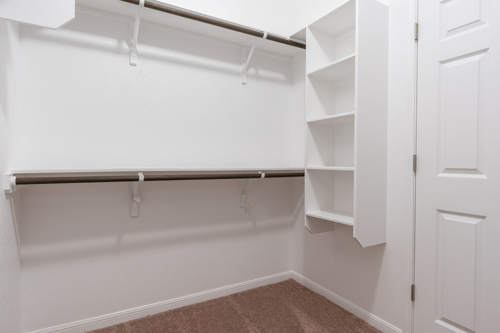Photo of a large arts and crafts gender-neutral walk-in wardrobe in Austin with open cabinets, white cabinets, carpet and beige floor.