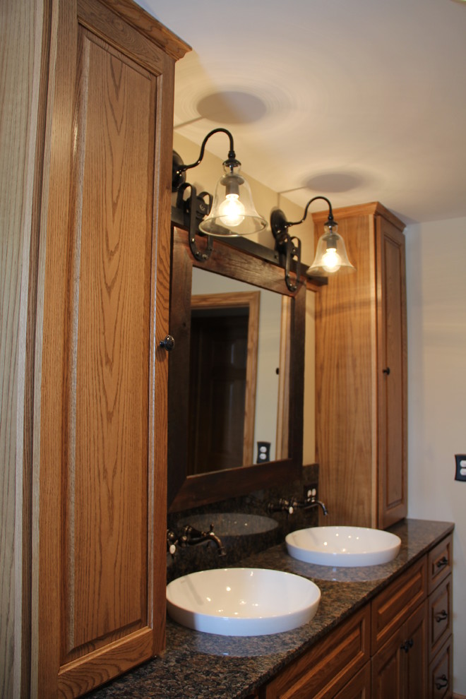 Tub/shower combo - transitional brown tile and porcelain tile porcelain tile tub/shower combo idea in Columbus with a vessel sink, an undermount tub, a two-piece toilet, raised-panel cabinets, medium tone wood cabinets, granite countertops and beige walls