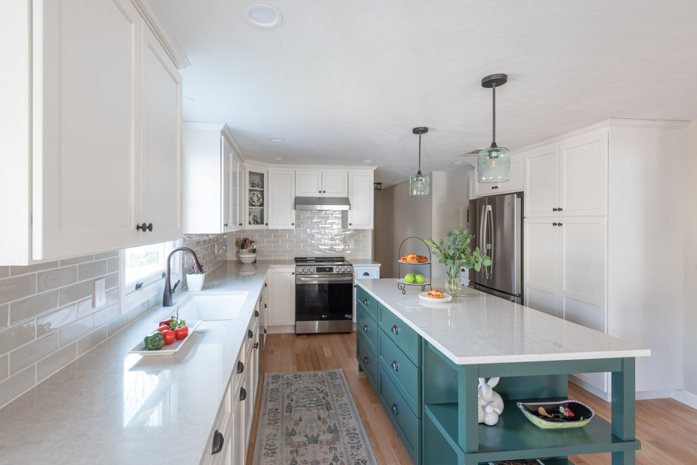 Eat-in kitchen - large transitional galley light wood floor and brown floor eat-in kitchen idea in Boston with an undermount sink, shaker cabinets, white cabinets, quartz countertops, beige backsplash, ceramic backsplash, stainless steel appliances, an island and white countertops