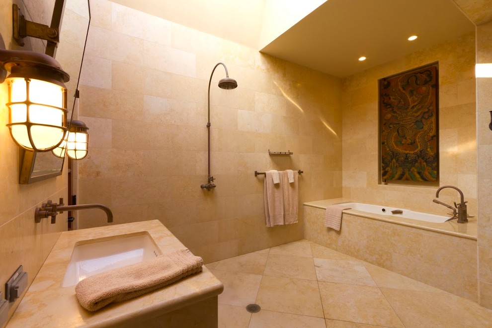 This is an example of a tropical bathroom in San Francisco with an undermount sink, an alcove tub and beige tile.