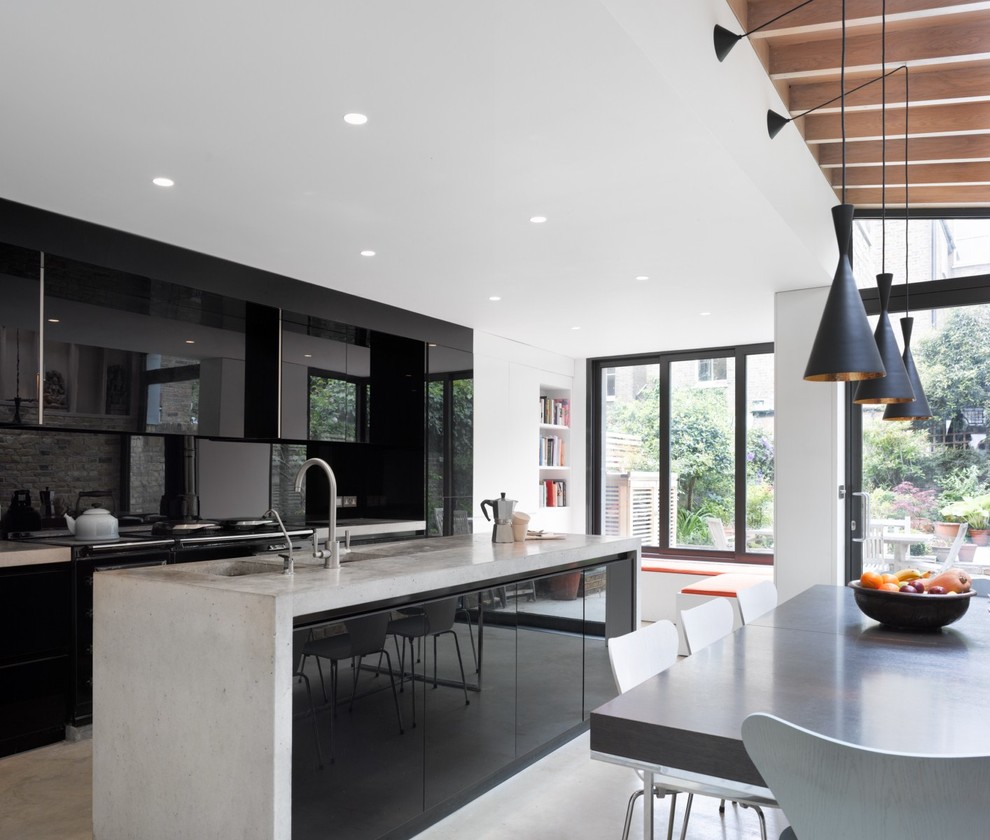 This is an example of a large contemporary eat-in kitchen in London with a double-bowl sink, flat-panel cabinets, black cabinets, concrete benchtops and with island.