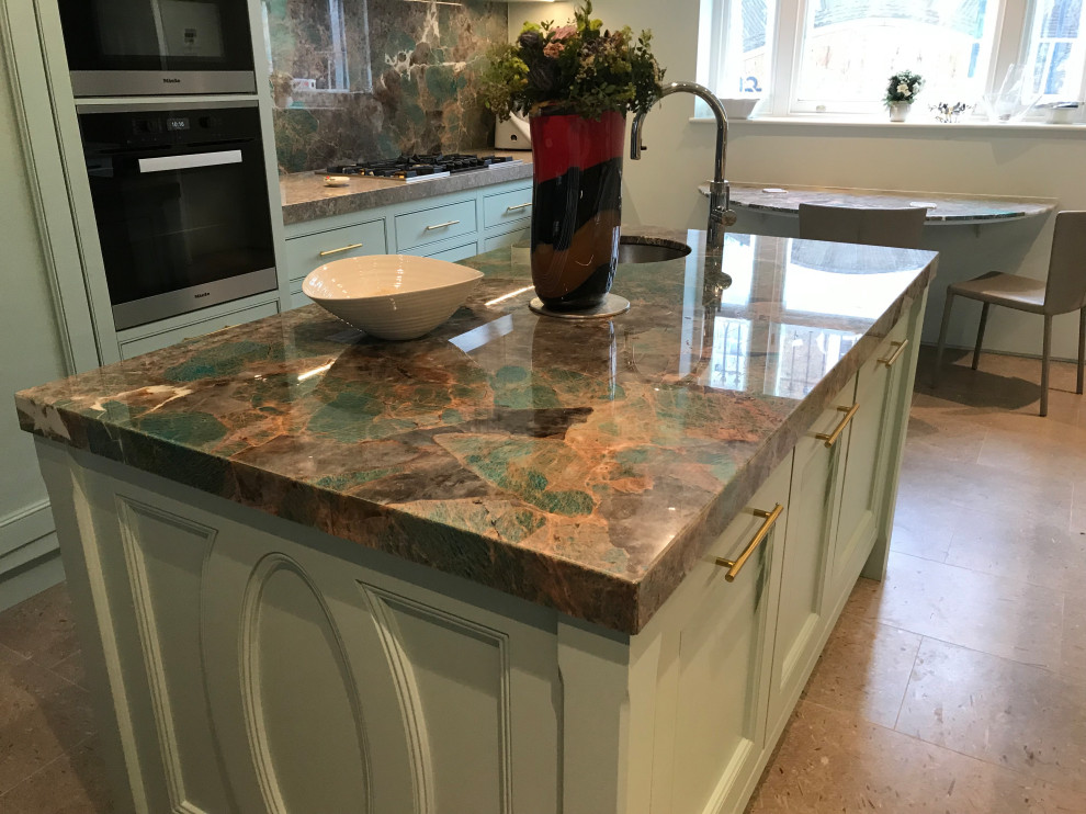 Photo of a large contemporary galley open plan kitchen in London with granite benchtops, multi-coloured splashback, limestone floors, with island, beige floor and multi-coloured benchtop.